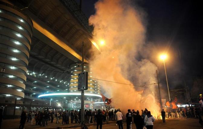 Fumogeni rossoneri accesi dai tifosi all'esterno dell'impianto milanese. Ansa